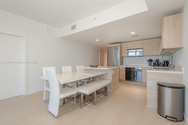 kitchen featuring light brown cabinets, stainless steel appliances, visible vents, light countertops, and modern cabinets