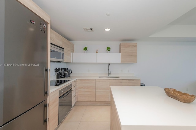 kitchen with light countertops, visible vents, light brown cabinets, a sink, and black appliances