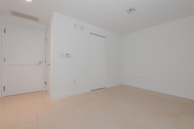 spare room with baseboards, visible vents, and light tile patterned flooring