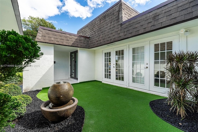 view of exterior entry featuring a lawn and french doors