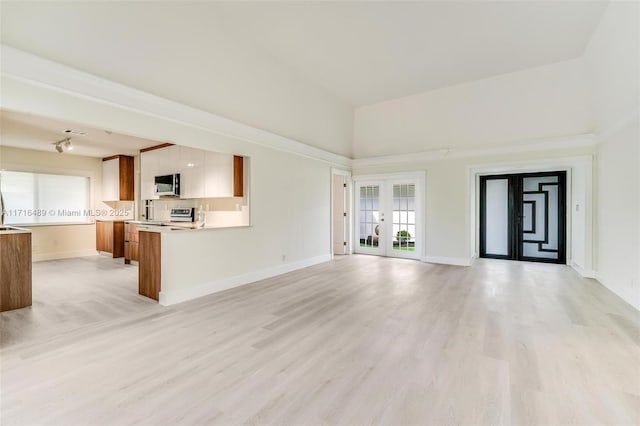 unfurnished living room with light wood finished floors, visible vents, baseboards, and french doors