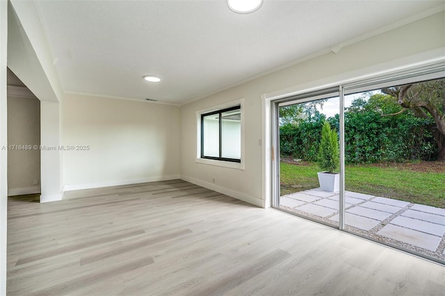 empty room with baseboards, ornamental molding, and light wood-style floors