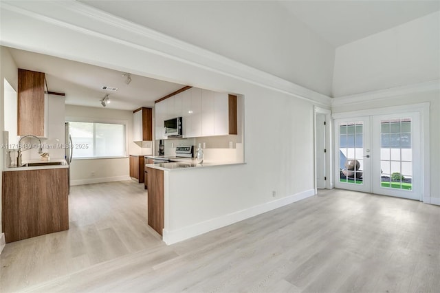 kitchen with stainless steel appliances, light countertops, french doors, white cabinetry, and a sink