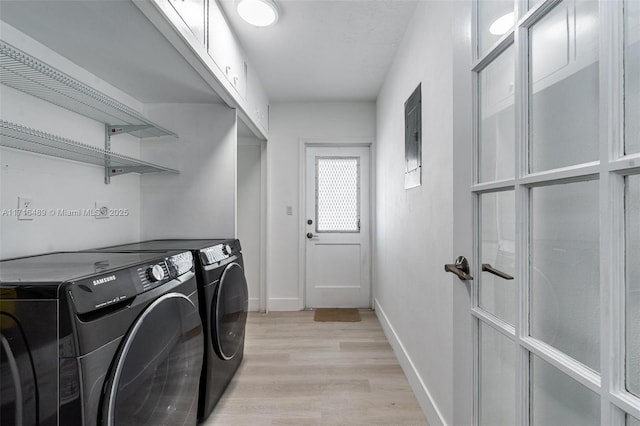 clothes washing area featuring washing machine and dryer, laundry area, light wood-style flooring, and baseboards