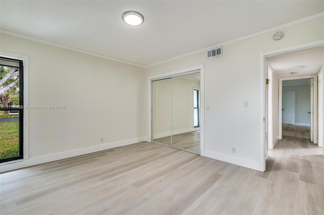 unfurnished bedroom featuring light wood finished floors, ornamental molding, visible vents, and baseboards