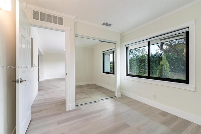 unfurnished bedroom featuring light wood-style flooring, visible vents, baseboards, and ornamental molding