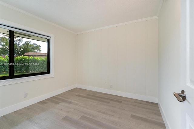 empty room with light wood-style floors, baseboards, and ornamental molding