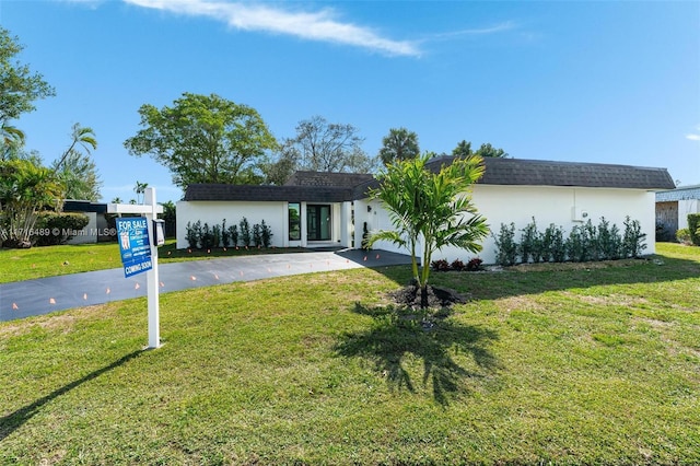 view of front of house with a front lawn, aphalt driveway, and stucco siding