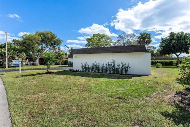 view of home's exterior with a yard, a shingled roof, and stucco siding