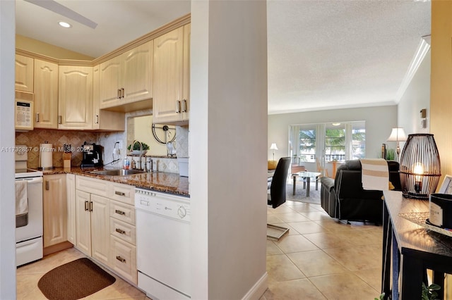 kitchen with sink, crown molding, dark stone countertops, light tile patterned floors, and white appliances