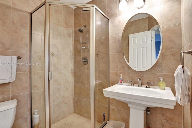 bathroom featuring walk in shower, decorative backsplash, toilet, and tile walls