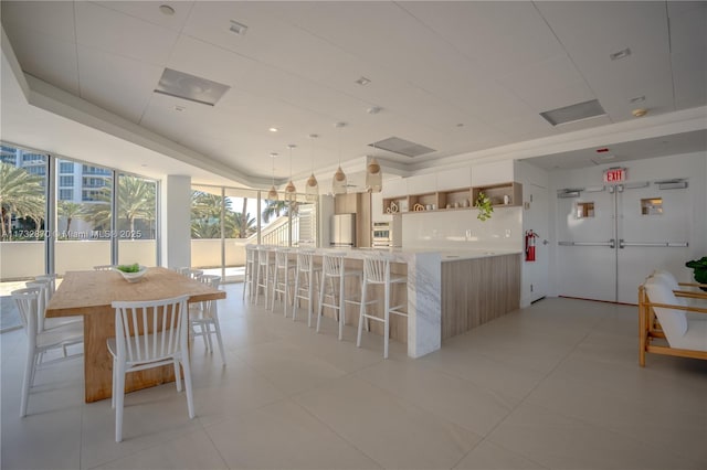 kitchen with pendant lighting, floor to ceiling windows, a spacious island, white refrigerator, and a kitchen bar