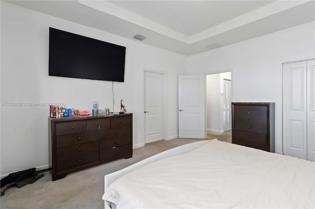 bedroom featuring a tray ceiling and light colored carpet