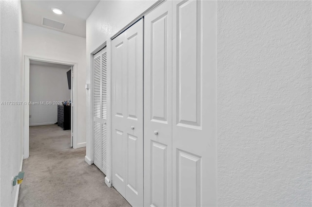 hallway featuring light colored carpet