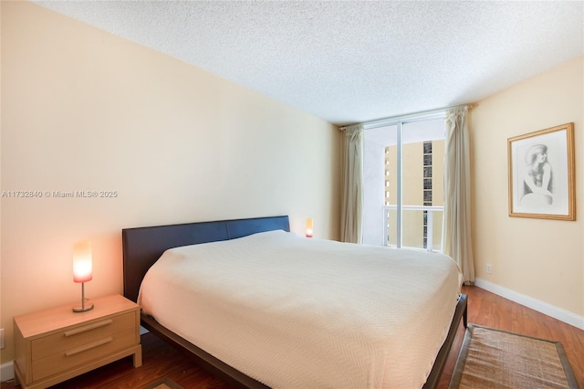 bedroom with floor to ceiling windows, dark wood-type flooring, and a textured ceiling