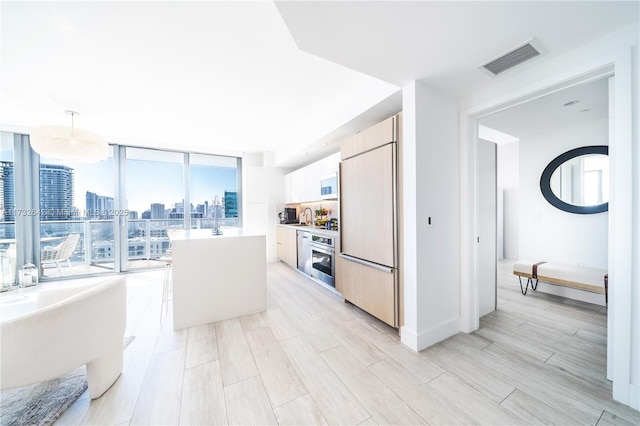 kitchen featuring hanging light fixtures, floor to ceiling windows, paneled fridge, a kitchen island, and oven