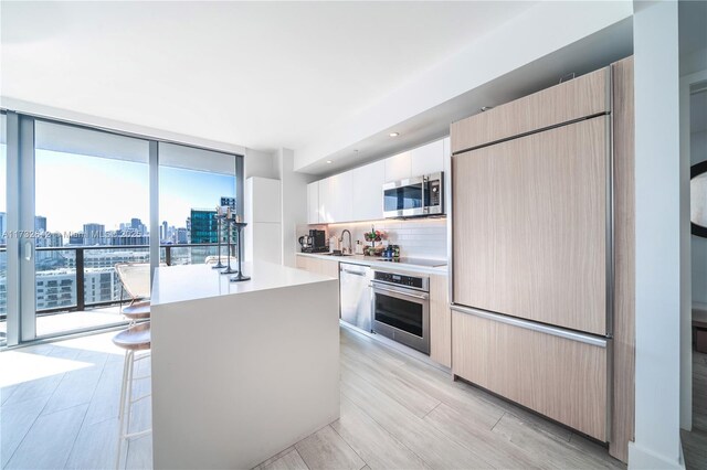 kitchen with floor to ceiling windows, a breakfast bar, sink, a center island, and stainless steel appliances