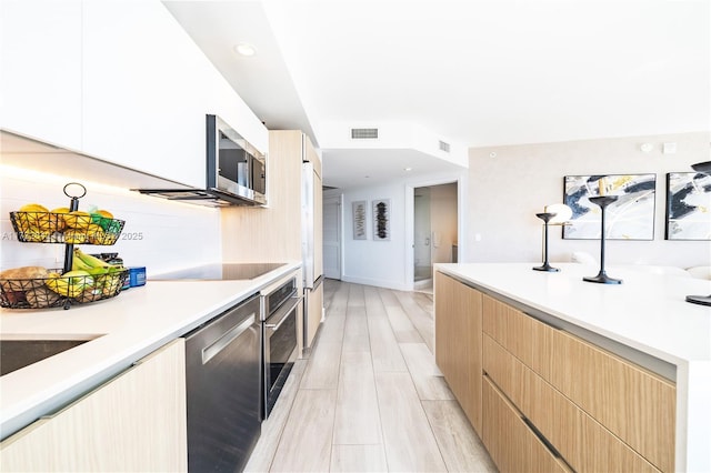 kitchen with appliances with stainless steel finishes, light brown cabinetry, and light hardwood / wood-style floors