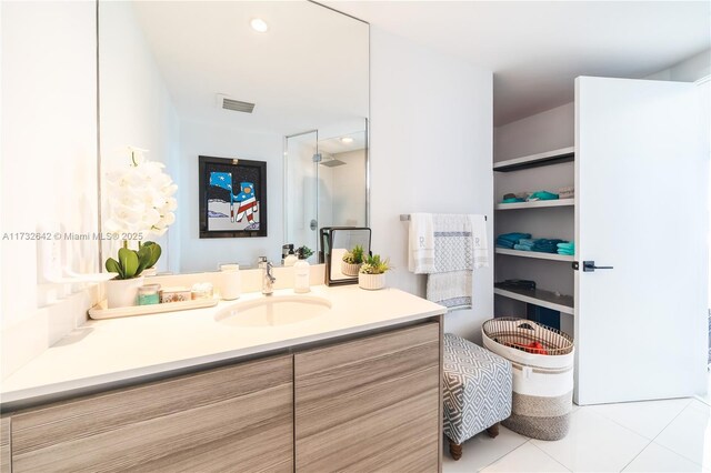 bathroom with tile patterned flooring, vanity, and walk in shower