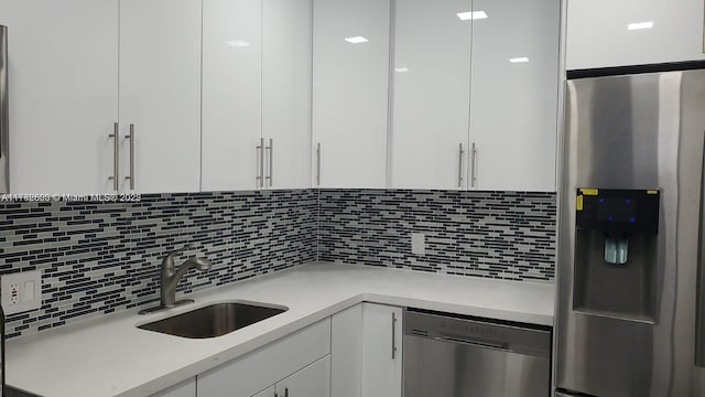 kitchen featuring white cabinetry, sink, backsplash, and appliances with stainless steel finishes