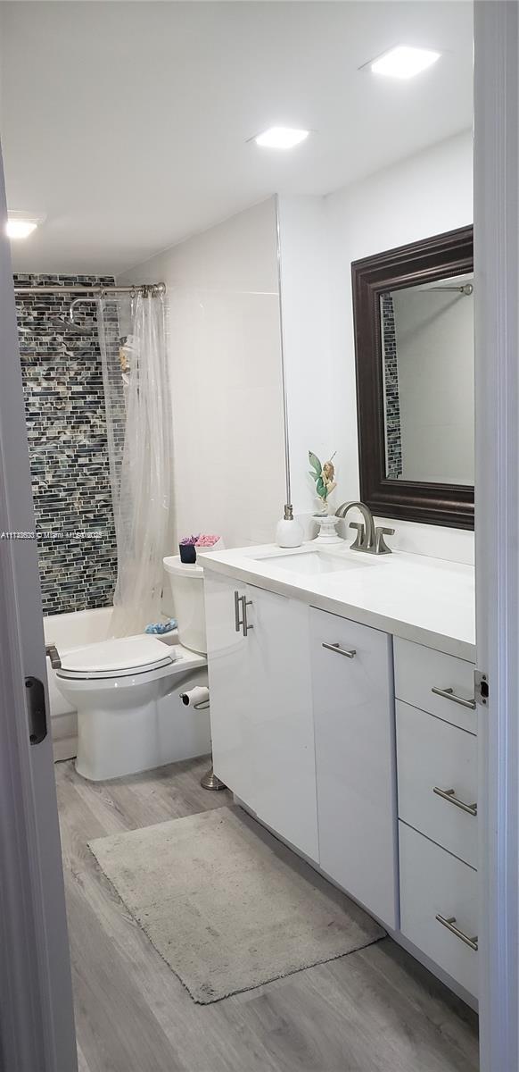 bathroom featuring vanity, hardwood / wood-style flooring, toilet, and walk in shower