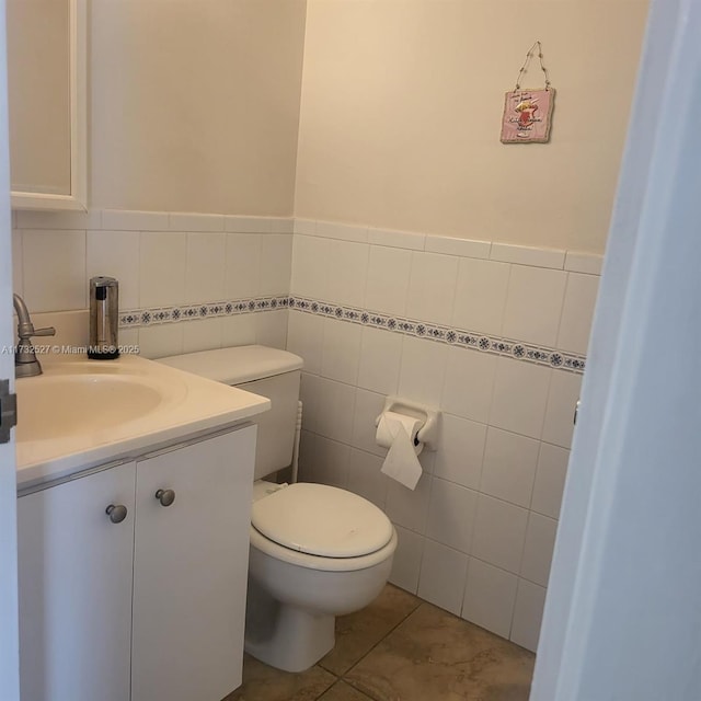 bathroom with vanity, toilet, tile patterned flooring, and tile walls