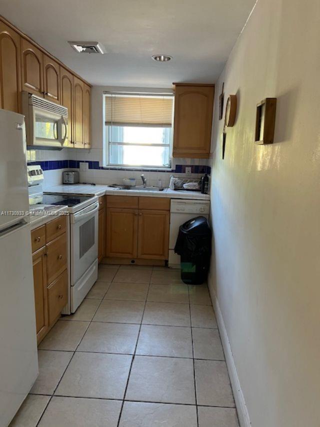 kitchen featuring light tile patterned flooring, sink, and white appliances