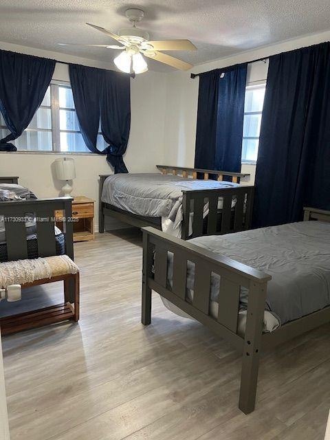 bedroom featuring hardwood / wood-style floors, a textured ceiling, and ceiling fan