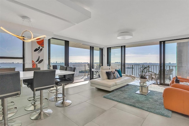 living room with tile patterned flooring, a water view, a notable chandelier, and a wall of windows