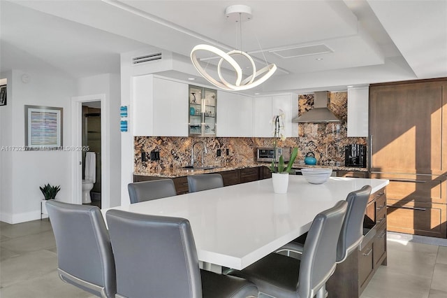 dining room featuring an inviting chandelier, a tray ceiling, sink, and light tile patterned floors