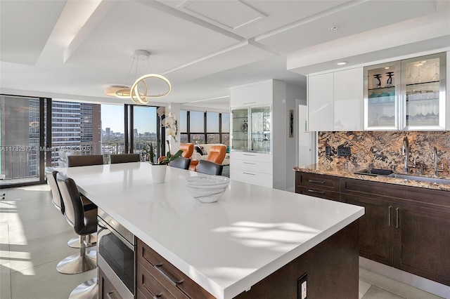 kitchen featuring sink, a breakfast bar area, white cabinetry, a center island, and hanging light fixtures