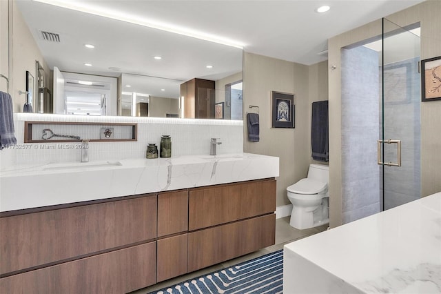 bathroom featuring toilet, a shower with shower door, vanity, and decorative backsplash