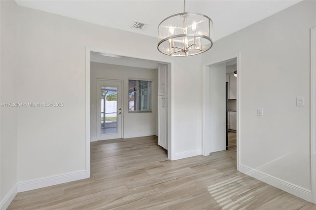 unfurnished dining area with an inviting chandelier and light hardwood / wood-style floors