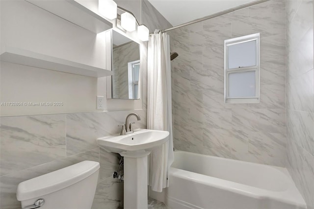 bathroom featuring toilet, shower / tub combo, and tile walls