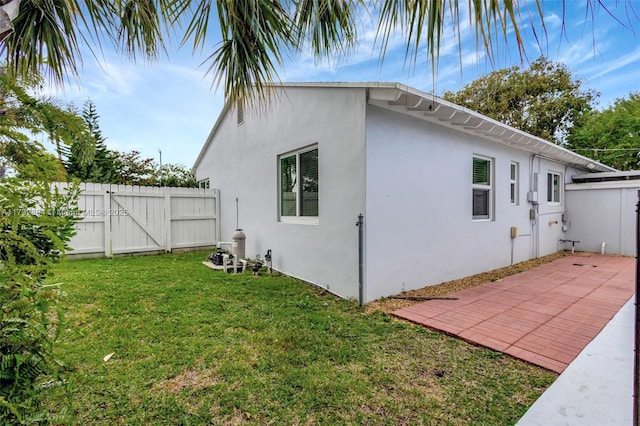 view of side of home with a lawn and a patio