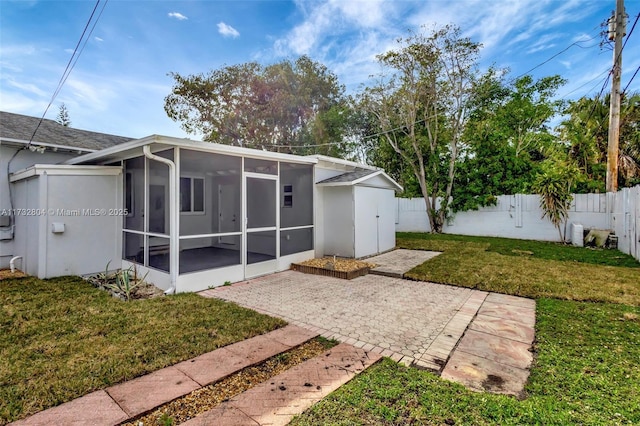 rear view of house with a sunroom, a yard, and a patio area