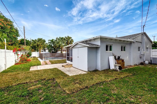 rear view of house featuring a fenced in pool, a patio, and a lawn