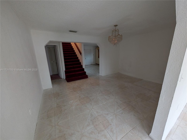 tiled empty room featuring a textured ceiling