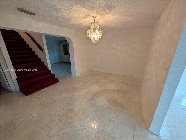 empty room with a textured ceiling and a notable chandelier