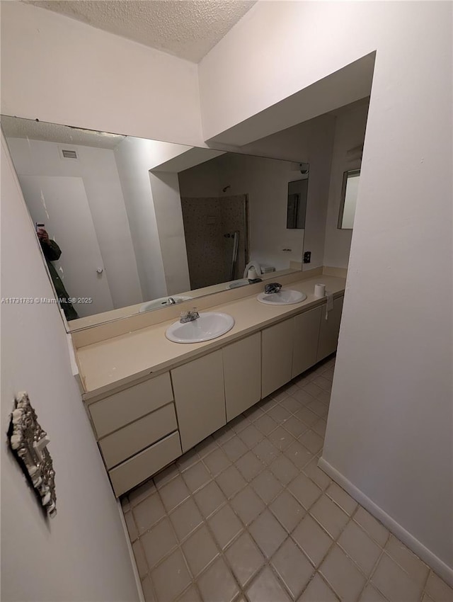 bathroom featuring vanity, tile patterned flooring, and a textured ceiling