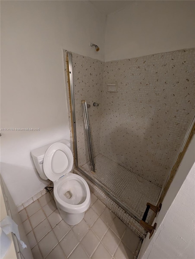 bathroom featuring a tile shower, tile patterned floors, and toilet