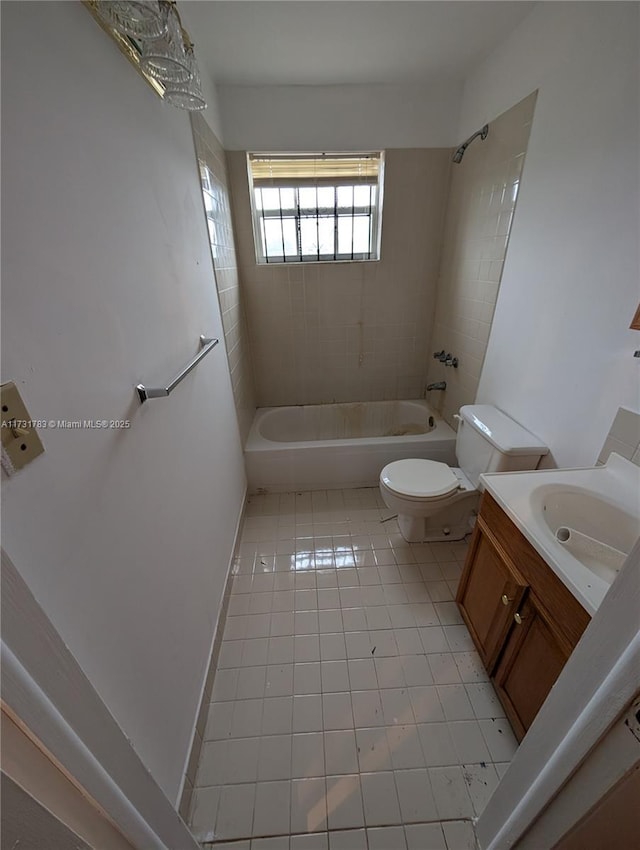 full bathroom with tiled shower / bath, tile patterned floors, toilet, and vanity