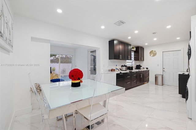 kitchen featuring stacked washer / dryer and dark brown cabinets