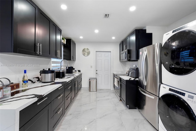 kitchen with stainless steel appliances, stacked washer and clothes dryer, and sink