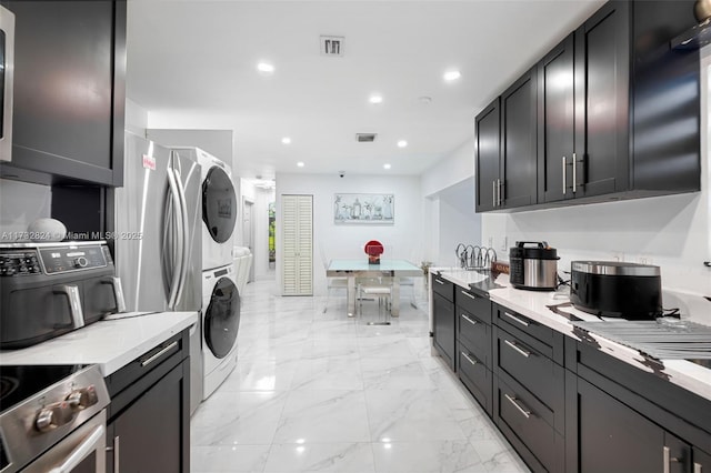 kitchen with stacked washing maching and dryer, stainless steel range with electric cooktop, and light stone counters