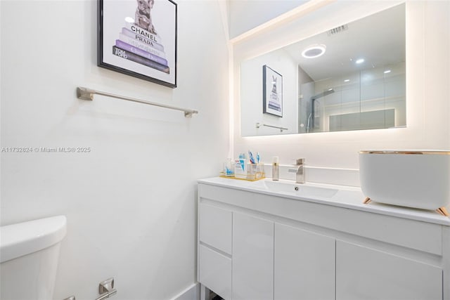 bathroom featuring a shower with door, vanity, and toilet