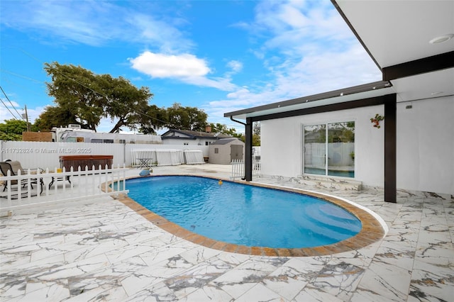 view of swimming pool with a shed and a patio area