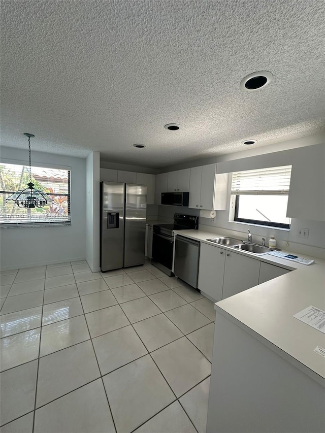 kitchen with white cabinetry, appliances with stainless steel finishes, decorative light fixtures, and a wealth of natural light