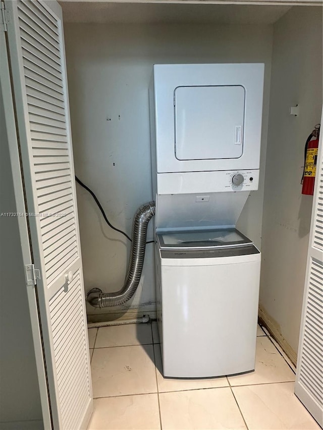 laundry area featuring light tile patterned flooring and stacked washer and clothes dryer