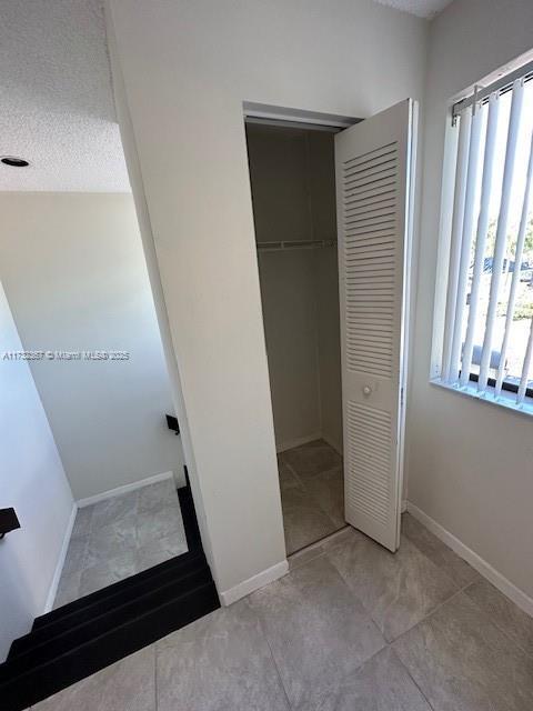 unfurnished bedroom with light tile patterned flooring, a textured ceiling, and a closet